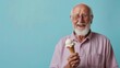 © Joyce - A senior male holding an ice cream and eating over plain background.