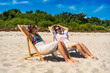 © Jacek Chabraszewski - Summertime on beach. Two young women of European beauty dressed in beach wear sitting on deckchairs on beach with white sand on beautiful sunny day. Relaxing on beach.