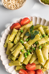 Wall Mural - Delicious pasta with fresh basil pesto, green peas, cherry tomatoes and cheese.