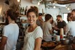 © Milos - A smiling woman stands in a cafe with friends in the background, highlighting a modern, lively ambiance and the vibrant social interactions that come with shared spaces.