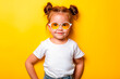 © Creative mind - Adorable stylish little Caucasian girl wearing a sunglasses and White plain White t-shirt with space for your print isolated on yellow background. Child's clothing mockup.