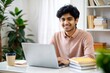 © N7 - Indian student sitting at desk with laptop and books
