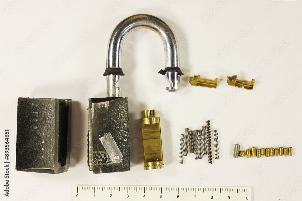 Disassembled padlock on a white background with a scale ruler, forensic ...