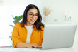 © Kateryna - Happy successful gorgeous arabian or indian ethnicity young woman with eyeglasses, company seo, creative manager, IT specialist sits at a work desk working in a laptop, looking device screen, smile