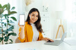 © Kateryna - Happy pretty arabian or indian young woman, product manager, web designer, sits at a work desk, showing mock-up empty white screen of device for advertising or presentation, looks and smiles at camera