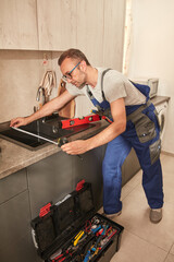 Wall Mural - Plumber fixing and repairing water tap on the kitchen sink.