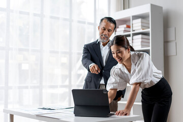 Wall Mural - A man and a woman are looking at a laptop together