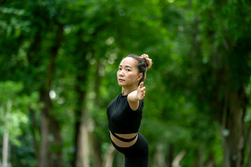 A woman is doing a yoga pose in a park