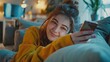 © Nijat - Sending happy messages. Lovely young lady lounging on the couch at home, grinning as she uses her smartphone