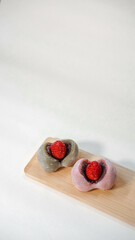 2 pieces of Japanese daifuku strawberry and matcha mochi filled with red bean paste, vertical