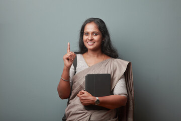 Wall Mural - Smiling Indian woman holding a tablet computer showing hand gesture