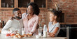 © Prostock-studio - Lovely black family of three having lunch at kitchen, drinking milk and eating pastry, copy space