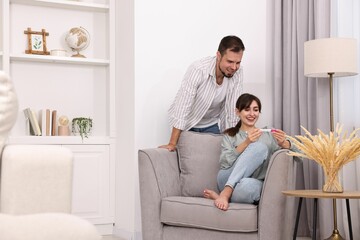 Wall Mural - Happy young couple with pregnancy test at home, space for text