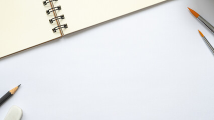 Wall Mural - open blank spiral notebook with paintbrush, pencil and eraser on white background, empty space for y