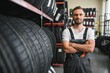 © Serhii - mechanic in blue uniform standing at stock tyre