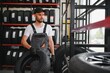 © Serhii - mechanic in blue uniform standing at stock tyre