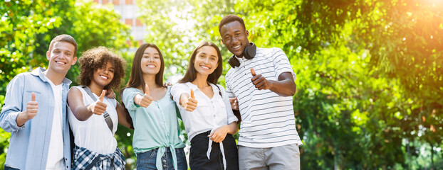 Group Of Multicultural Teen Friends Posing At Camera Outdoors And Gesturing Thumb Up, Panorama