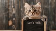 © TENTIP - Cute kitten holding a small chalkboard with the text 'Let's talk'. Adorable cat with curious expression offering conversation.