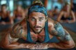 © DachAI - A fit yoga instructor with tattoos is in focus, engaged in an intense exercise, leading a workout session. Other participants are visible in the background of the studio.