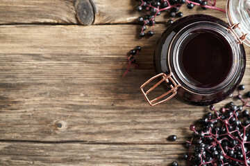 Wall Mural - Homemade black elder syrup with fresh elderberries on wooden background with copy space