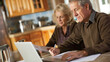 © VK Studio - A senior couple works together at a kitchen table, focusing on paperwork and a laptop, illuminated by natural light.