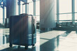 A lone navy suitcase stands in the sunlit airport terminal, signifying the quiet anticipation of travel yet to come.