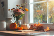 © Victor Bertrand - A cozy autumnal kitchen with sunlight filtering through a window, featuring a bouquet of flowers and small pumpkins, creating a warm and inviting atmosphere.