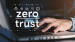 © deimos.az - The hand of a business man using a laptop with security icons and the text 'zero trust' on a virtual screen
