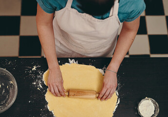 Baking, dough and hands with baker in kitchen of home, cooking ingredients for recipe from above. Food, pastry and rolling pin with chef person in apron for preparation of cake, cookies or dessert