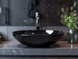 © vefimov - A modern and minimalist bathroom featuring a sleek black sink on a marble countertop, with a high-end faucet and well-lit ambiance.