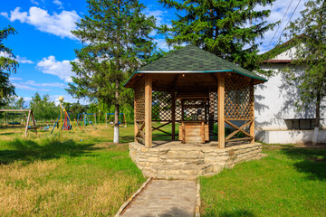 Wall Mural - A wooden pavilion with a roof and a small table, rural well