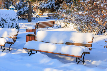 Wall Mural - A park with a bench covered in snow, winter background or backdrop