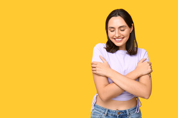 Sticker - Young woman hugging herself on yellow background