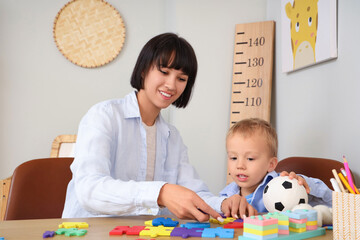 Poster - Young mother with her little son doing puzzle at home