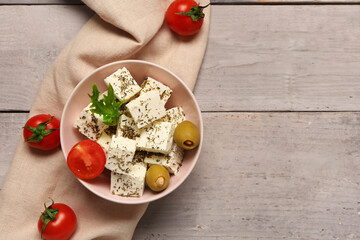 Wall Mural - Bowl with cubes of feta cheese, cherry tomatoes, olives and lettuce on grey wooden background