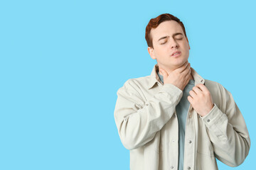 Wall Mural - Young man with sore throat on blue background