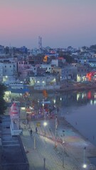 Wall Mural - View of famous indian hinduism pilgrimage town sacred holy hindu religious city Pushkar with Brahma temple, aarti ceremony, lake and ghats illuminated at sunset. Rajasthan, India. Horizontal pan