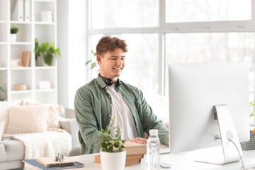 Wall Mural - Male student studying online with computer at home