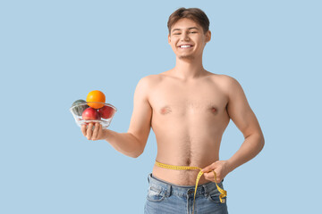 Poster - Sporty young man with fruits and measuring tape on light background. Weight loss concept