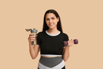 Canvas Print - Beautiful young happy woman with dumbbell and sports bottle of water on beige background