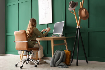 Wall Mural - Young woman drinking coffee in stylish office