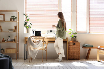 Poster - Young woman drinking coffee near workplace in stylish office