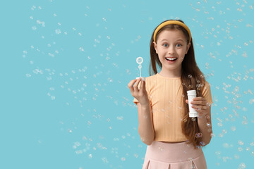 Poster - Happy girl blowing soap bubbles on blue background