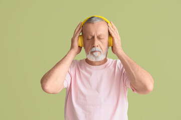 Poster - Mature man in headphones listening to music on green background