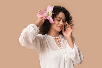 Poster - Beautiful young African-American woman with pink lily flower on beige background