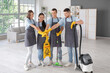 © Pixel-Shot - Group of young janitors with cleaning supplies putting hands together in room