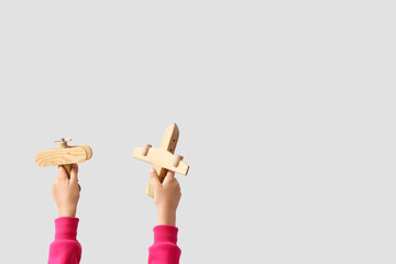 Wall Mural - Child with wooden planes on light background