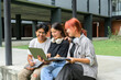 © Parichat - Group of Diverse Students Studying Together Outdoors with Laptops and Notebooks at Modern University Campus