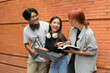 © Parichat - Group of Happy Students with Laptops and Notebooks Socializing Against a Brick Wall Background