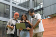 © Parichat - Group of Happy Students Collaborating Outdoors with Laptop in Modern Campus Setting